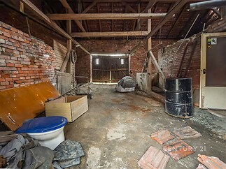 Prostorná garáž s cihlovými zdmi, dřevěnými trámy a betonovou podlahou nabízí možnost rekonstrukce a přizpůsobení prostoru dle potřeb majitele.