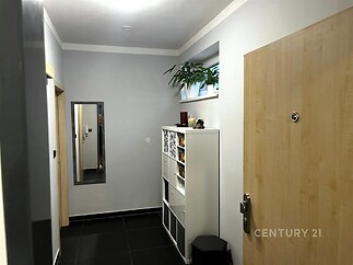 Vstupní hala s dlažbou, bílá vestavěná skříň a zrcadlo, moderní design, neutrální barvy, světlé stěny, dobře osvětlený prostor.