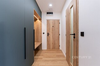 Vstupní hala s dřevěnou podlahou, vestavěné skříně v moderním stylu a dveře z přírodního dřeva.