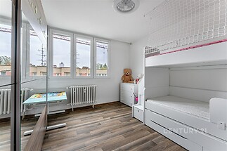 Dětský pokoj s parketovou podlahou, velkými okny a vestavěnými skříněmi působí moderně a svěže.