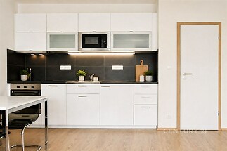 Moderní kuchyň s parketovou podlahou, vestavěnými spotřebiči a elegantními bílými skříňkami v minimalistickém stylu.