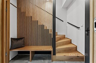 Vstupní hala se dřevěným schodištěm, moderní dřevěné obložení, dlažba na podlaze, stylový minimalistický design.