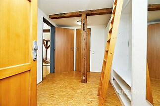 Chodba s dřevěnými prvky a parketovou podlahou, vestavěné police, moderní osvětlení, dveře z masivního dřeva.