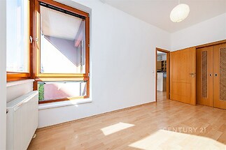 Světlý pokoj s parketovou podlahou, velkými okny a vestavěnými skříněmi, vhodný pro moderní bydlení.