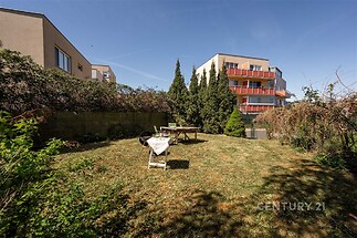 Prostorná zahrada s udržovaným trávníkem a keři, orientovaná na jih s dostatkem slunečního světla, ideální pro relaxaci nebo zahradničení.