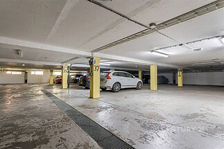 Praktické podzemní garážové stání s betonovou podlahou, dobrá osvětlení a značená parkovací místa pro pohodlné parkování v moderní budově.