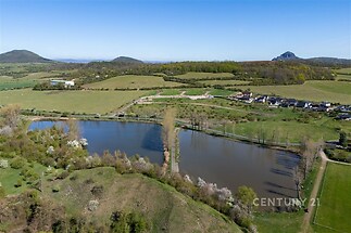 Jezero v malebné krajině, obklopené loukami a lesem, ideální pro rekreační využití nebo investici do přírodního prostředí