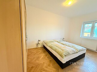 Světlá ložnice s parketovou podlahou, vestavěné skříně a velká okna poskytují moderní a prostorný vzhled.