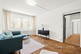 Světlý obývací pokoj s parketovou podlahou, velká okna, moderní vybavení, útulný interiér s elegantním nábytkem a výhledem do zahrady.