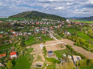 Stavební pozemek na okraji obce, obklopený zelení a kopci, s možností výstavby rodinného domu v klidné lokalitě.