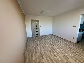 Světlý obývací pokoj s parketovou podlahou, moderní design, neutrální barvy stěn, prostorný a připravený k zařizování.