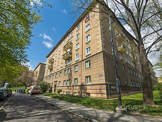 Exteriér bytového domu se zateplenou fasádou, balkony a udržovanými veřejnými prostory, klidná lokalita poblíž centra města.