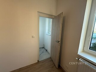 Malý pokoj s parketovou podlahou, moderní dveře z dřeva a velké okno, které zajišťuje dostatek denního světla.