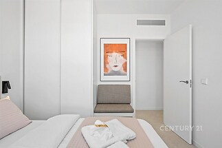 Světlá ložnice s vestavěnými skříněmi a moderním dekorem, bílými stěnami a světlou parketovou podlahou, nabízí klidné bydlení.