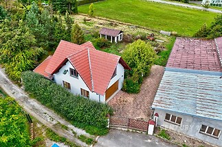 Rodinný dům se sedlovou střechou, červená tašková krytina, velká okna, oplocená zahrada, klidná lokalita.
