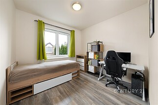 Prostorný dětský pokoj, dřevěná podlaha, velká okna, moderní zařízení s psacím stolem a úložnými prostory, světlý interiér.