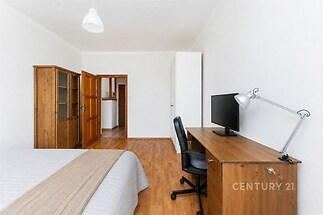 Prostorná ložnice s dřevěným nábytkem, parketovou podlahou a velkou vestavěnou skříní, nabízí moderní a útulný styl.
