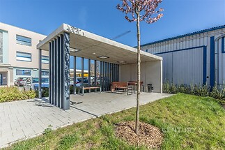 Venkovní zastřešená terasa s moderním betonovým přístřeškem, dlážděná podlaha, lavičky, ideální pro relaxaci.