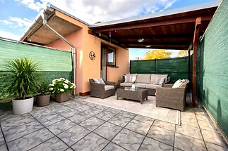 Krytá terasa s moderním nábytkem, dlažba a zelené prvky, ideální pro relaxaci.