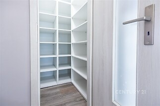 Praktická spíž s bílými policemi, světlá dřevěná podlaha, moderní dveře s úchyty, ideální pro organizaci a skladování potravin