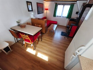 Světlý obývací pokoj s parketovou podlahou a velkým oknem, moderní nábytek, útulný styl, dobře osvětlený prostor.