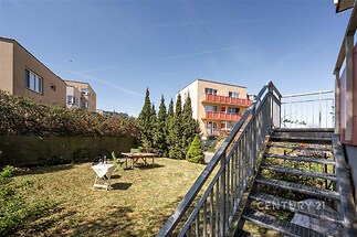 Soukromá zahrada s pečlivě udržovaným trávníkem, kovové schody vedoucí na terasu, ideální pro relaxaci, oplocený prostor pro bezpečnost