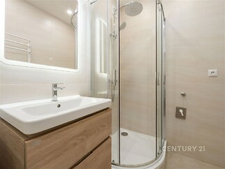 Koupelna s moderním sprchovým koutem, světlými dlaždicemi a dřevěnou skříňkou pod umyvadlem, minimalistický design a čisté linie