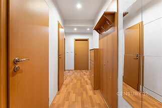 Chodba s parketovou podlahou a vestavěnými skříněmi, moderní styl a dřevěné dveře, nabízí dostatek úložného prostoru.