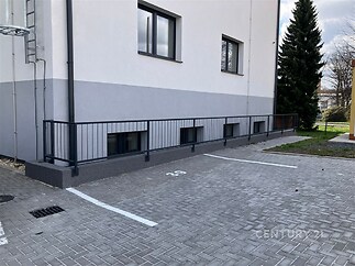 Prázdné parkovací stání s dlažbou před moderní budovou.