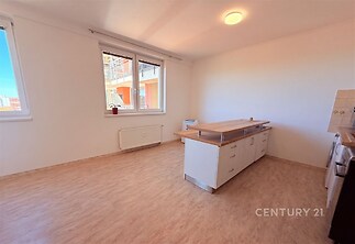 Světlá kuchyň s parketovou podlahou, moderní kuchyňský ostrůvek a velká okna pro přirozené osvětlení.
