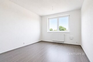 Světlá ložnice s parketovou podlahou, velká okna zajišťující dostatek přirozeného světla, moderní vzhled čisté stěny.