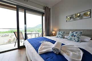 Prostorná ložnice s parketovou podlahou a velkými okny, moderní interiér, přístup na soukromý balkon s výhledem na krajinu.