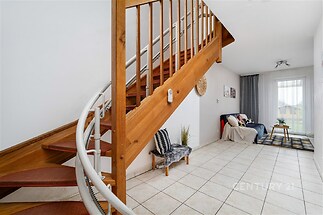 Schodiště s dřevěnými prvky a keramickou dlažbou, moderní design, světlá místnost díky velkým oknům s výhledem do zahrady.