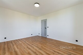 Prázdný pokoj s parketovou podlahou, světlý interiér a moderní bílou výmalbou, vhodný pro rekonstrukci nebo přizpůsobení dle přání.