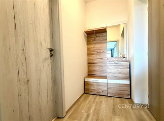 Předsíň s dřevěným nábytkem, laminátovou podlahou a velkým zrcadlem, moderní styl a světlé odstíny interiéru.