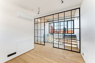 Světlý obývací pokoj s parketovou podlahou a velkými skleněnými dveřmi, moderní interiér a klimatizace, ideální prostor pro komfortní bydlení.