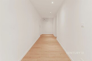 Úzká chodba s parketovou podlahou, bílými stěnami a vestavěným osvětlením, moderní minimalistický design