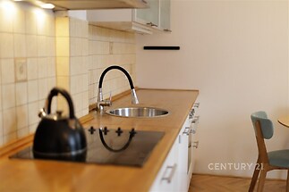 Kuchyň s dřevěnou pracovní deskou, moderní varná deska, parketová podlaha, světlý interiér