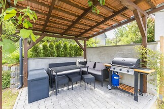 Zahradní terasa s pergolou, moderní dlažbou a zahradním nábytkem, ideální pro relaxaci a grilování, součástí je i plynový gril