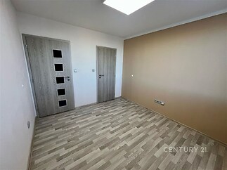 Prázdný pokoj s dřevěnou podlahou, moderními dveřmi a světlými stěnami, ideální pro personalizaci a zařízení dle vlastního vkusu.