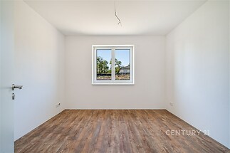 Prázdný pokoj s parketovou podlahou a velkým oknem, moderní styl, připravený k nastěhování.