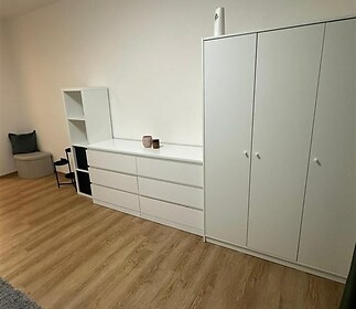 Světlá ložnice s parketovou podlahou, moderní vestavěné skříně a minimalistický styl, které vytvářejí vzdušný dojem.