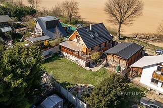 Rodinný dům s prostornou terasou a zahradou, obklopený zelení a přírodou. Atraktivní lokalita, moderní střešní krytina, klidné prostředí.