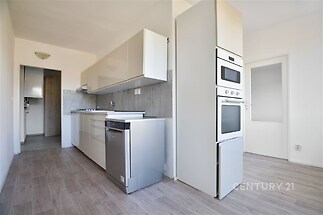 Moderní kuchyň s parketovou podlahou, bílá vestavěná skříň, nerezové spotřebiče, světlý interiér