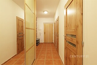 Předsíň s dlažbou a vestavěnou skříní, dřevěné dveře, světlá chodba, moderní interiér.