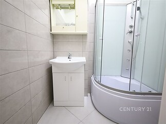 Koupelna s moderním sprchovým koutem, světlou dlažbou a úložnou skříňkou, vhodná pro rekonstruovaný byt.