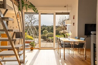 Jídelna s velkými okny nabízí výhled do zahrady, parketová podlaha a moderní nábytek vytváří světlý a příjemný prostor.