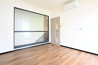 Prázdný pokoj s parketovou podlahou a moderní klimatizací, prosklená stěna dává prostoru světlost.