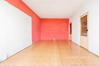 Prázdný obývací pokoj, parketová podlaha, výrazné červené stěny, moderní interiér, rekonstrukce potencial.