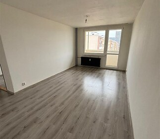 Prostorný obývací pokoj s moderní vinylovou podlahou, velká okna nabízejí dostatek přirozeného světla, pokoj je připraven k rekonstrukci